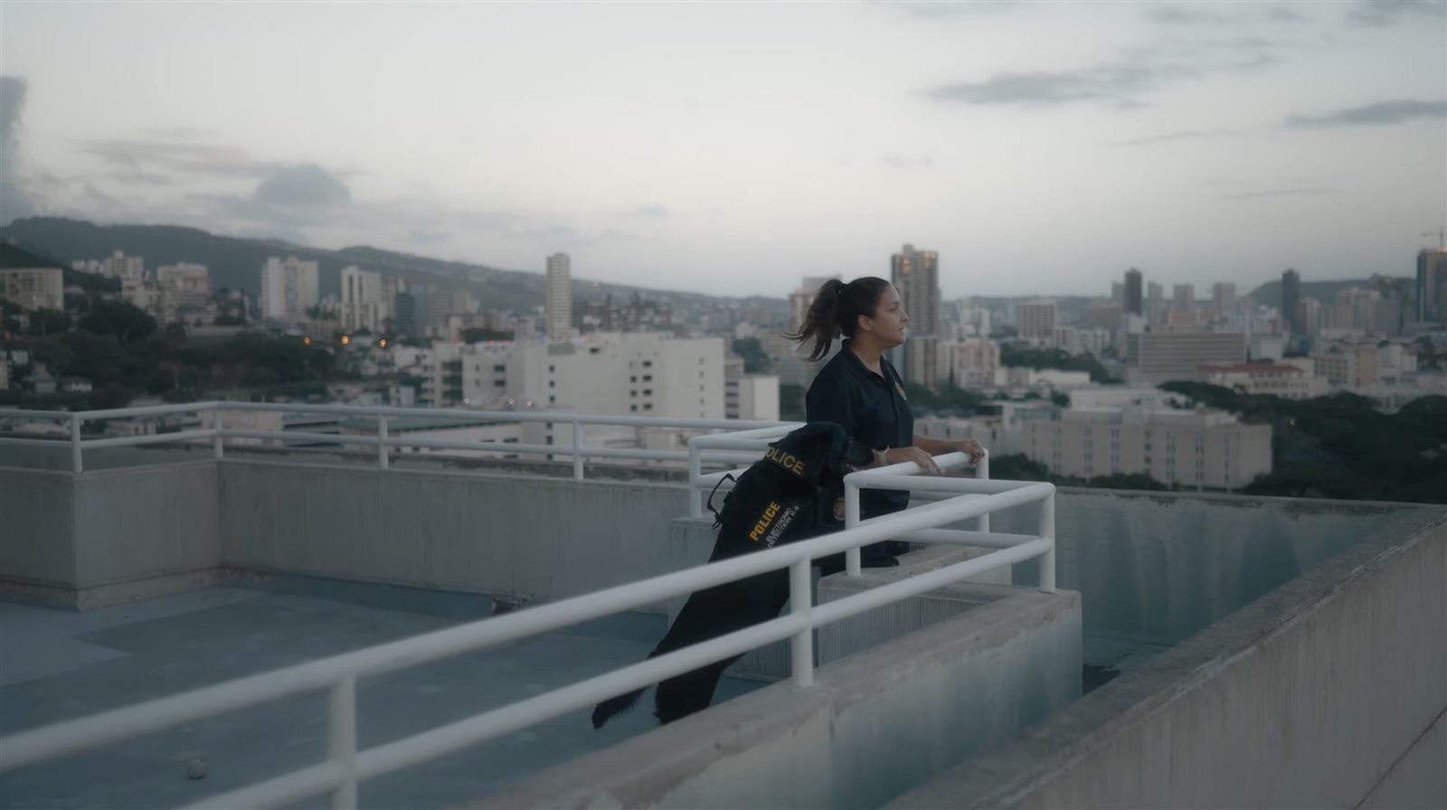 Alani and her K-9 partner Lulu looking out over the city at dusk
