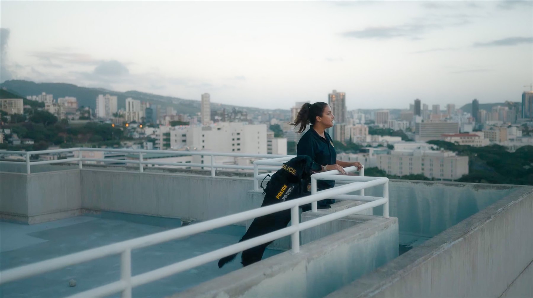 Alani Bankhead and her K-9 partner Lulu on a Honolulu rooftop, overlooking the city skyline