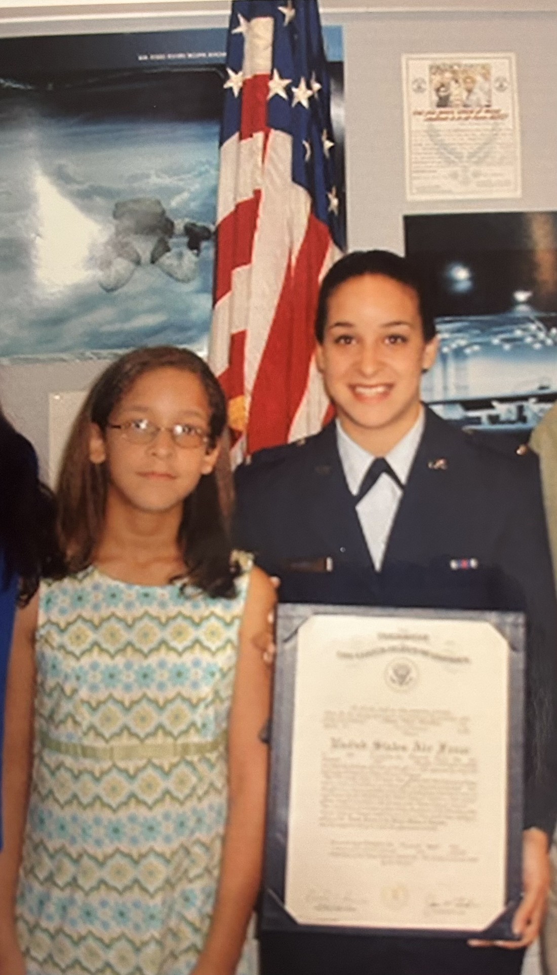 Alani Bankhead in Air Force dress blues as a newly commissioned second lieutenant, holding her commission certificate, standing with her sister.