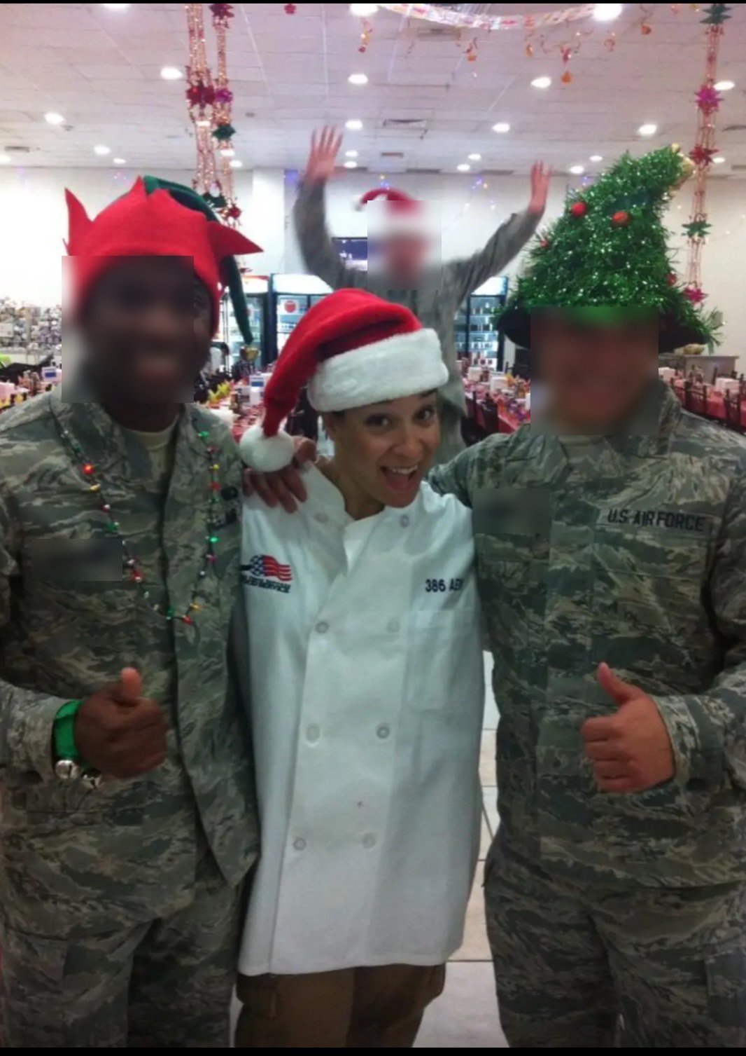 Alani Bankhead in a chef coat and a Santa hat, standing with two airmen at the holiday meal on deployment.